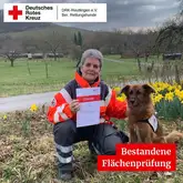 Rettungshundeteam zeigt stolz die Urkunde nach erfolgreicher Prüfung in der Fläche