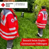 Besuch beim Kepler-Gymnasium Tübingen 2024 Zwei Einsatzkräfte stehen auf der Wiese, ein Border Collie läuft auf sie zu