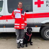 Eddit und Ralf Rettungshundeteam nach der Prüfung mit der Urkunde vor einem Einsatzwagen