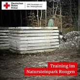 Titelbild Training im Natursteinpark Rongen 2026 Aufgestapelte Natursteine mit Person darauf sitzend und Hund mit Kenndecke lehnt sich dagegen