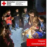 Titelbild Unsere Gemeinschaft 2025 Gemeinschaft steht im Kreis mit einem Campingtisch mit Verpflegung und essen gemeinsam