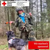 Wir machen es spannend Person mit Tarnanzug tanzt vor Rettungshund